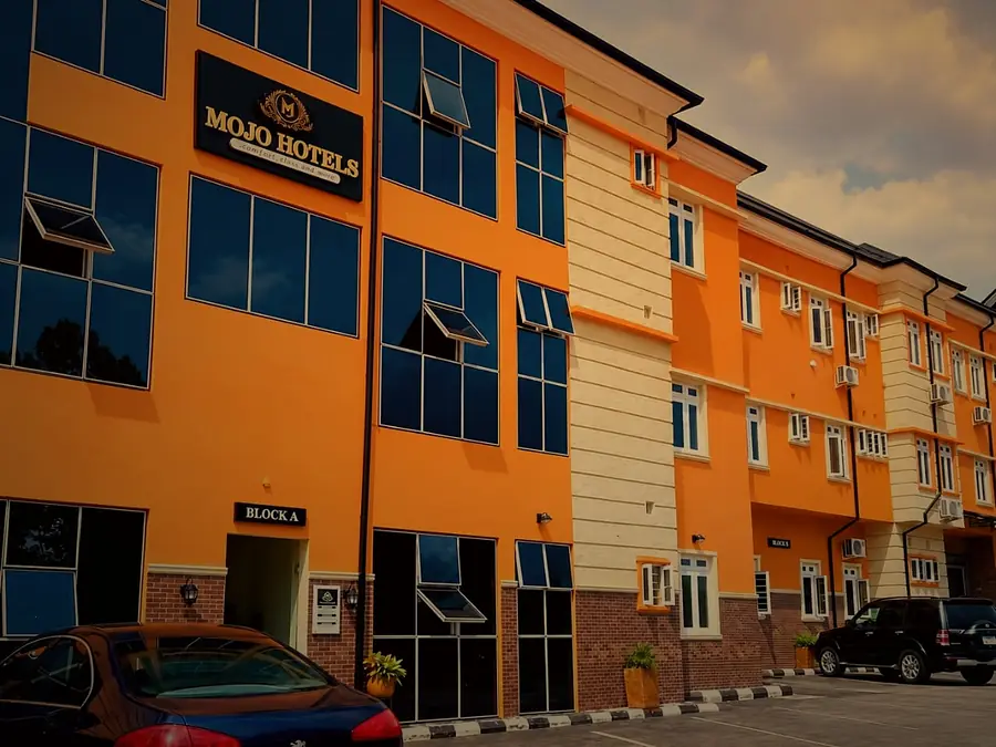 The Mojo Hotels building: orange three-storey blocks with blue glass windows and the gold crest sign
