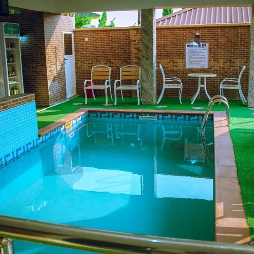 The hotel swimming pool with poolside chairs and a table